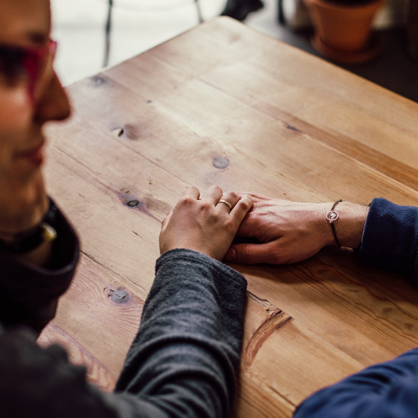 Two people hold hands at table